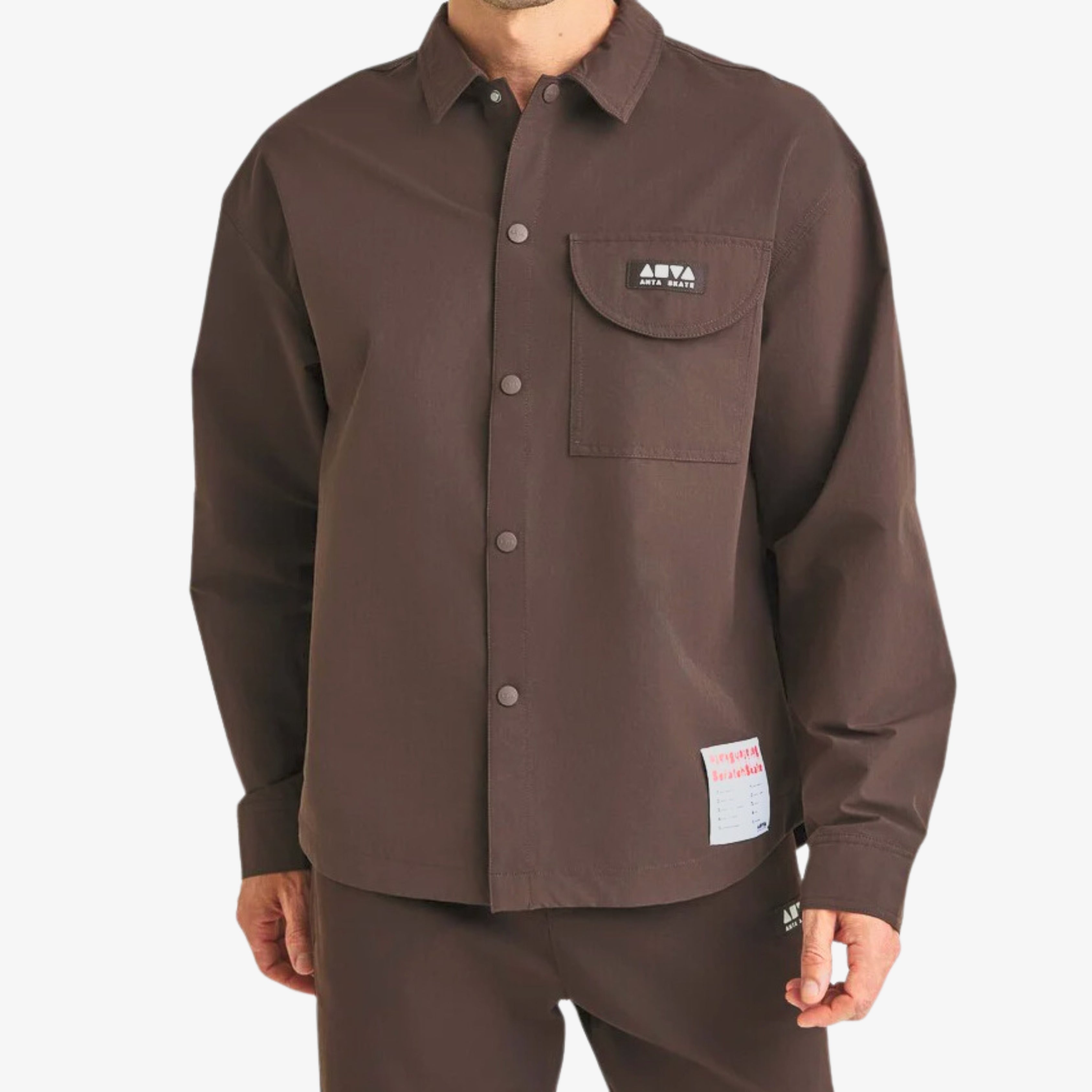 Chemise marron Anta oversize avec poche à rabat et logo brodé, style casual premium – Anta brown oversize shirt with flap pocket and embroidered logo, premium casual style.

