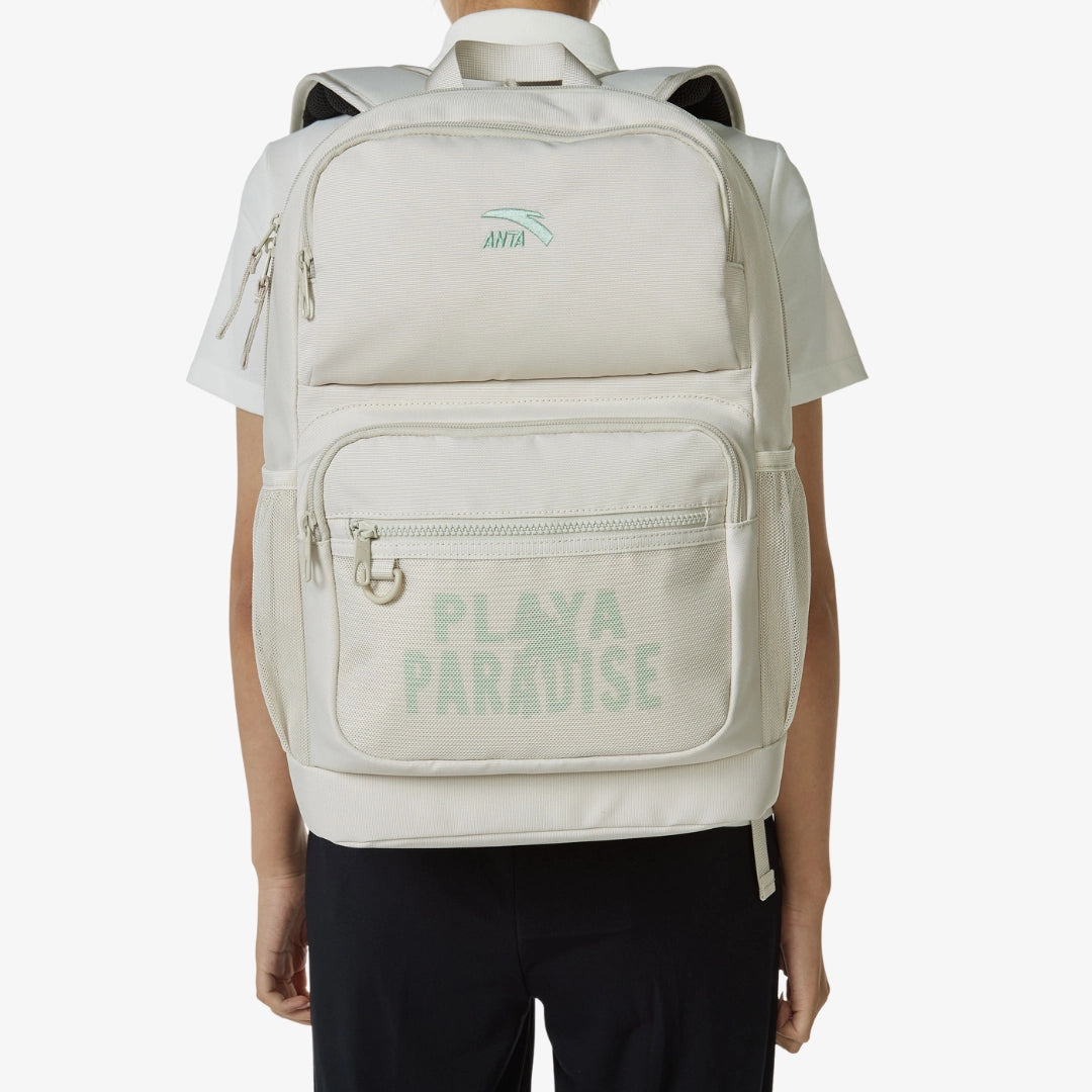 Sac à dos blanc Anta Playa Paradise porté par une personne, avec poches zippées et logo vert imprimé.